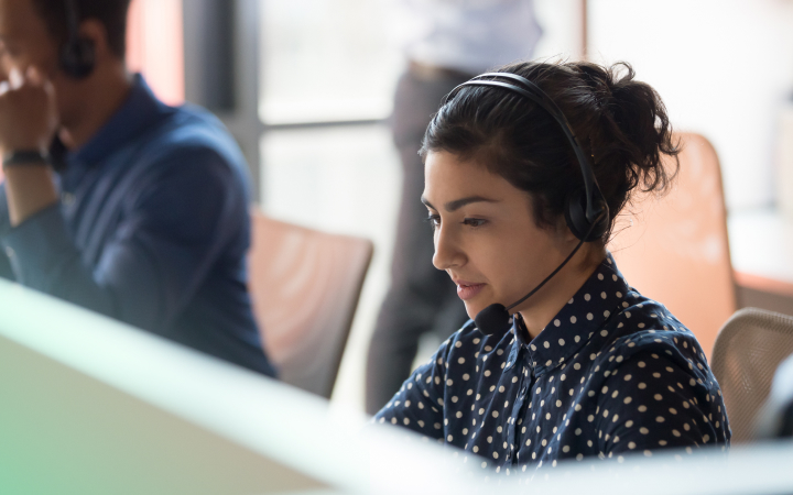A woman in a contact centre  is wearing a headset