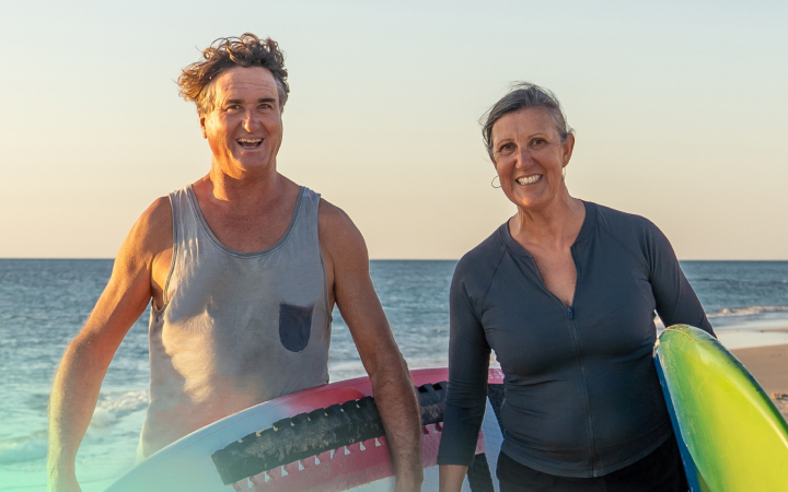 A happy couple holding surfboards at a beach