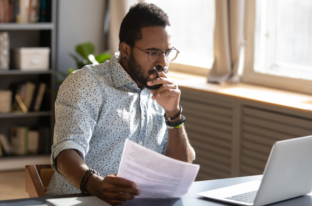 Man looking at laptop and paper