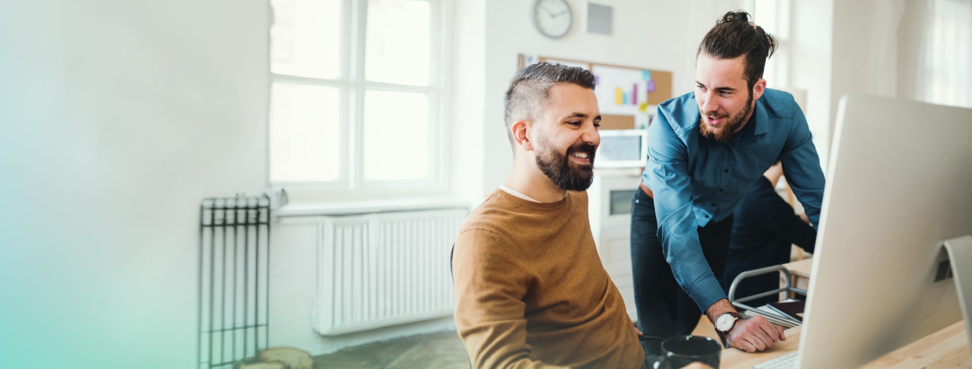 two self employed men are talking and working on an computer