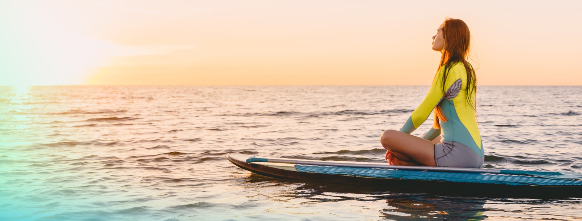 a girl is sitting on a kayak in ocean looking at the sunset