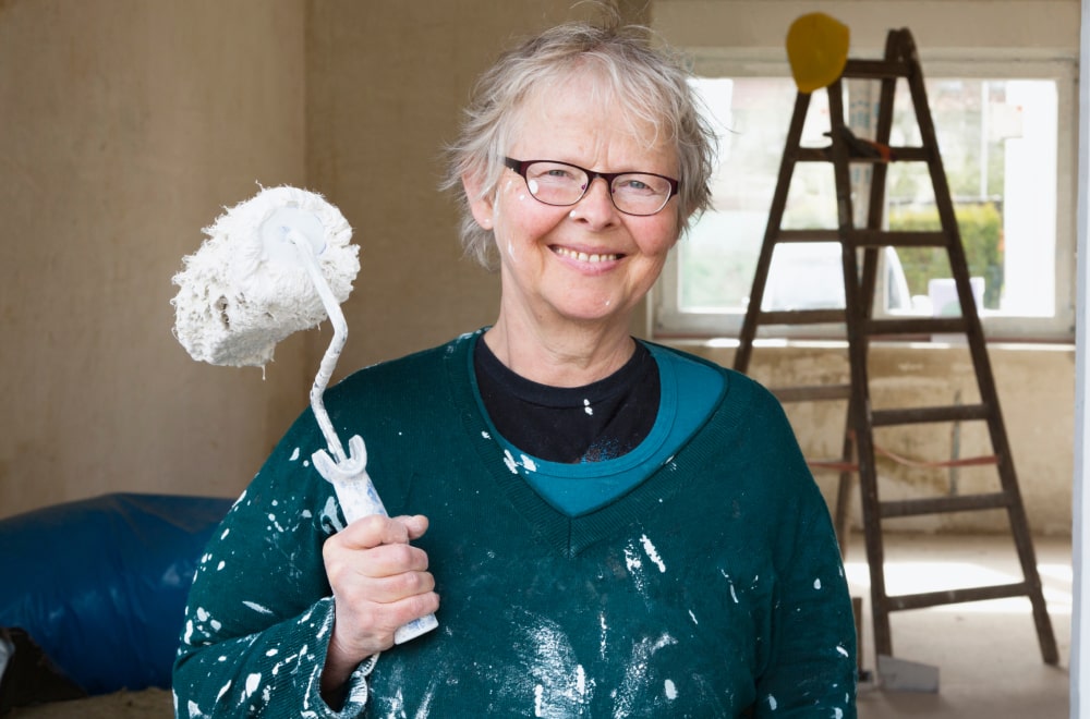 a elder woman is painting her house