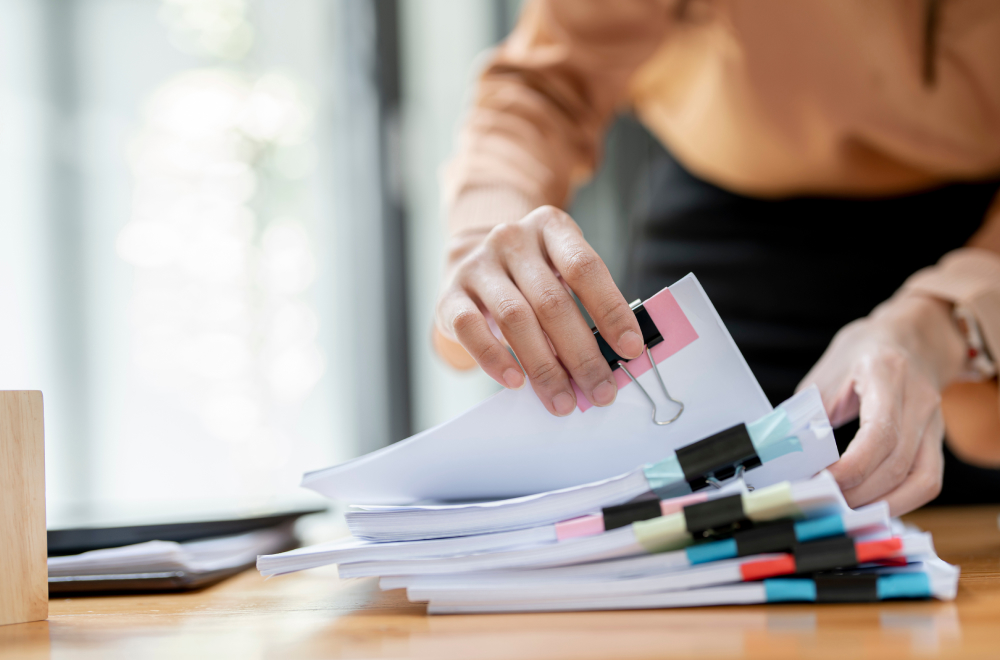 a woman is looking at a stack of paper