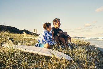 A father and his kid are sitting at the beach