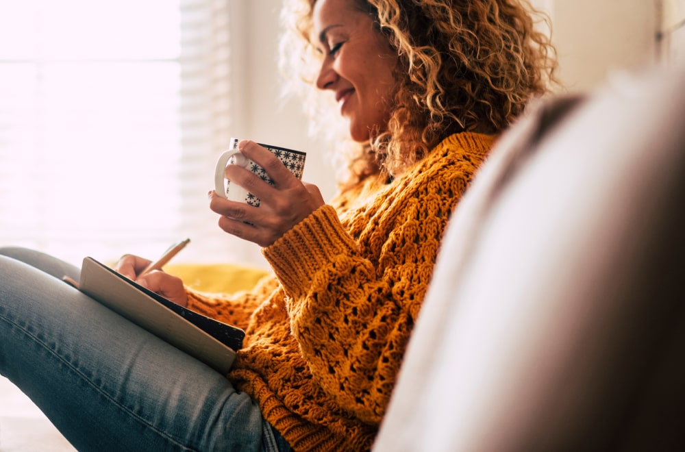 a happy woman is sitting on the couch working on a check list