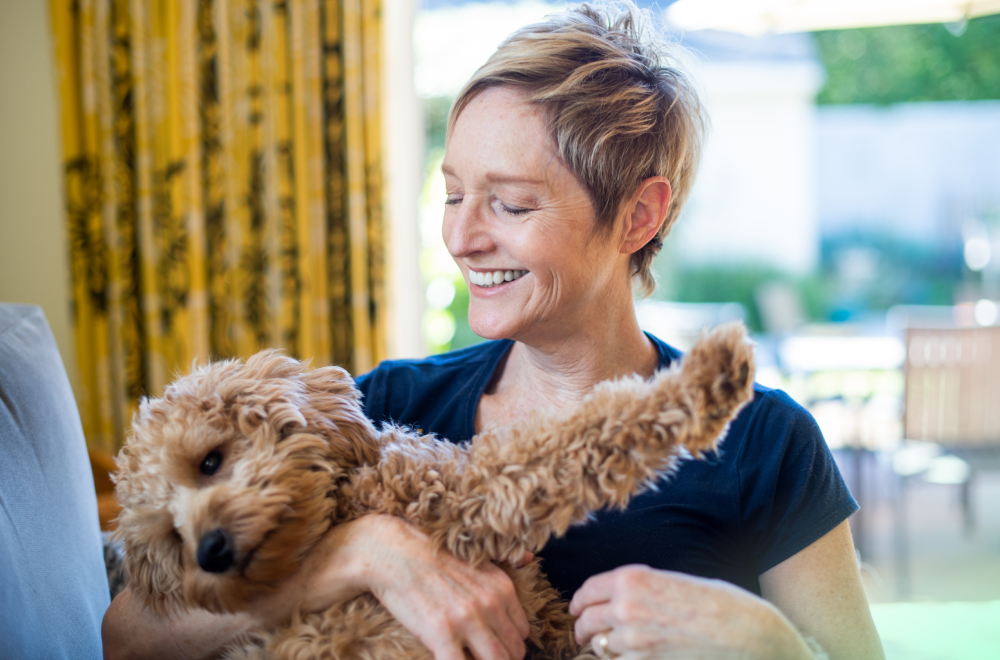 a happy woman is holding a puppy