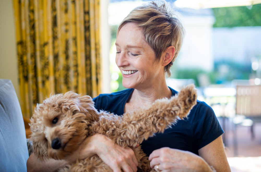 a happy woman is holding a puppy