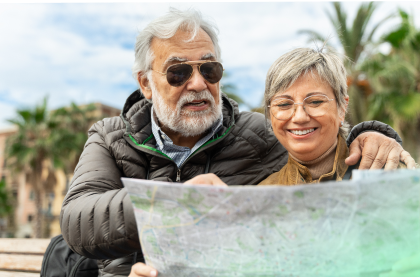 A happy elderly couple is holding and looking at the map
