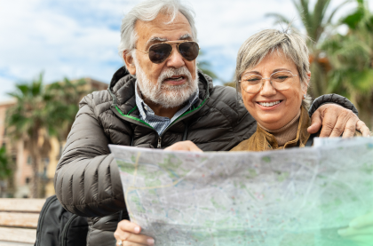 A happy elderly couple is holding and looking at the map
