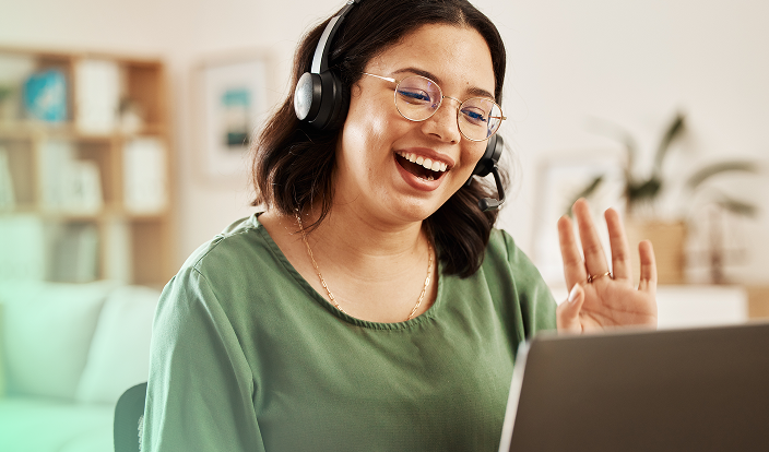 A happy lady wearing headsets joining online event on her laptop